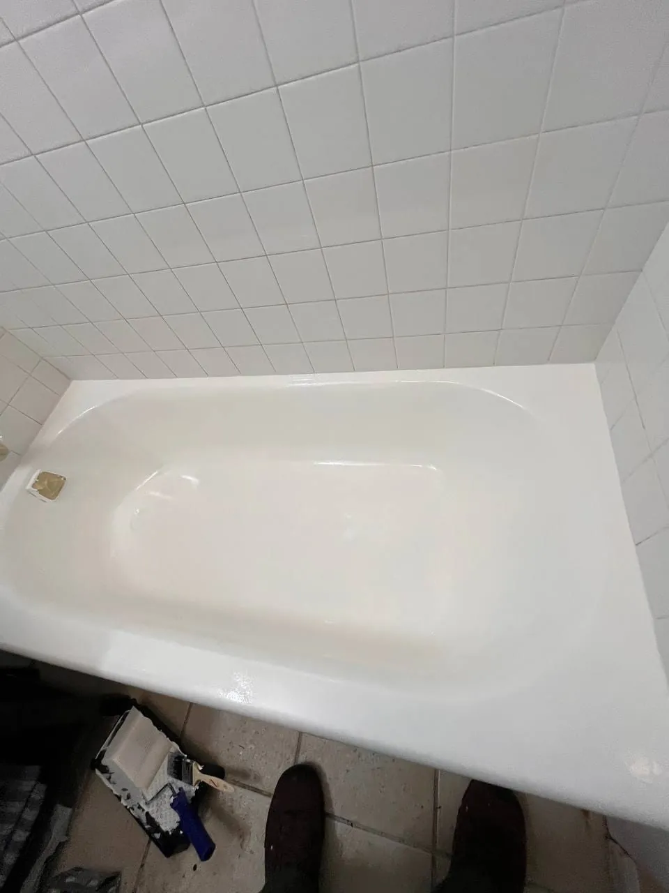 The refinished tub, white and glossy, tiled wall above