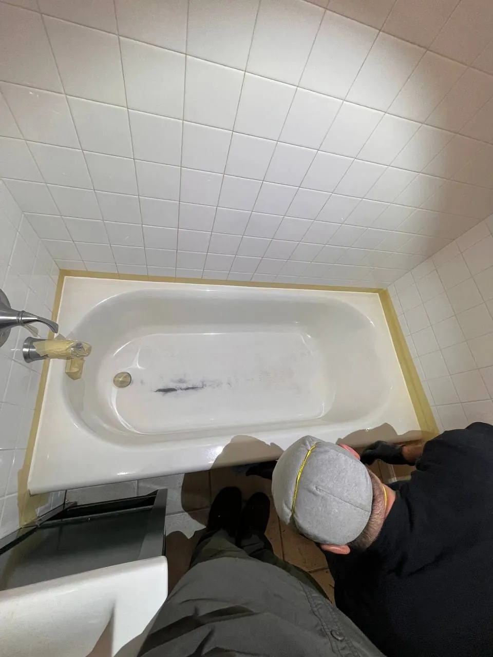 A bathtub taped off around the edges while being refinished