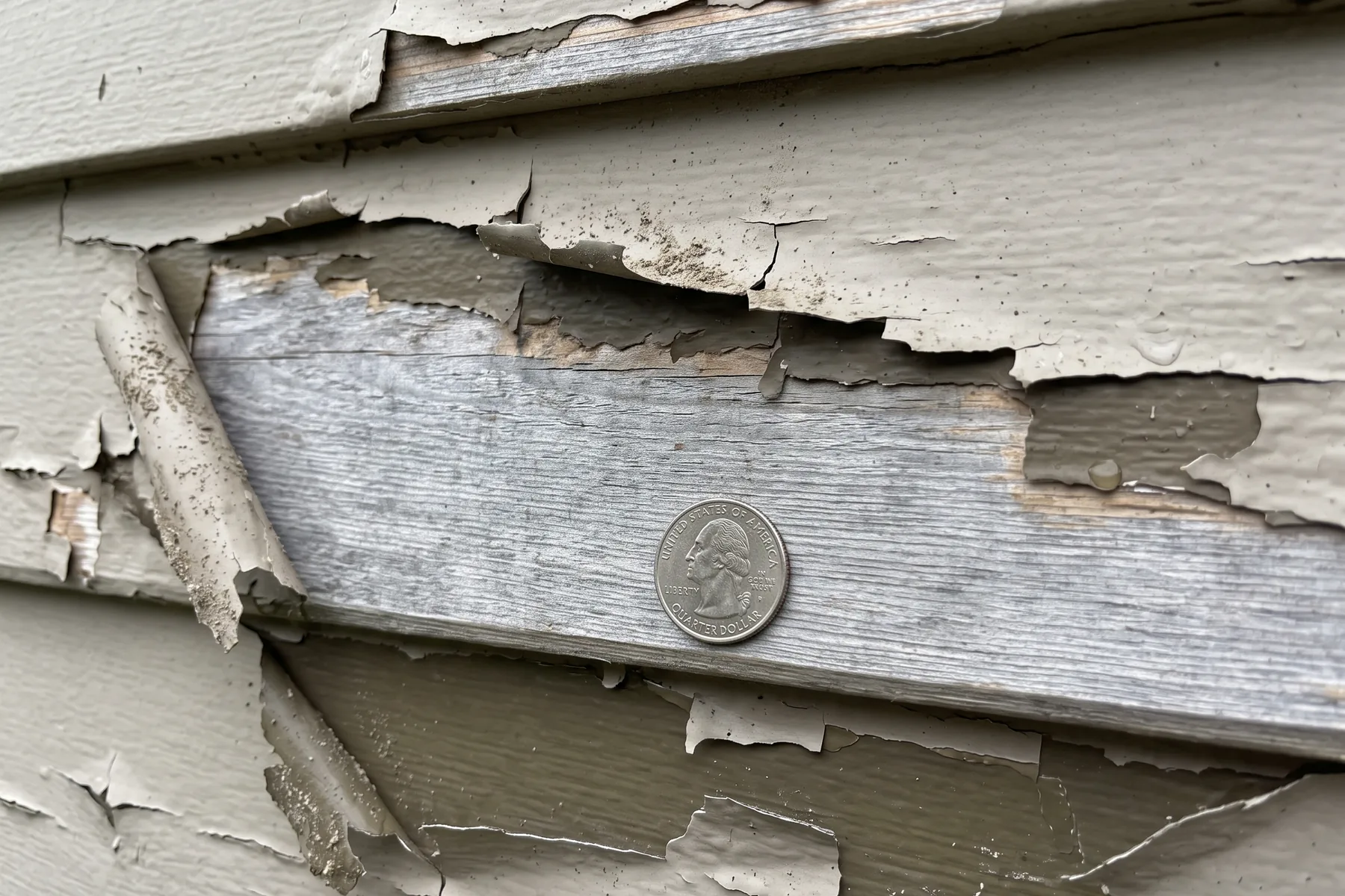 Close-up of paint flaking away from weathered wooden siding