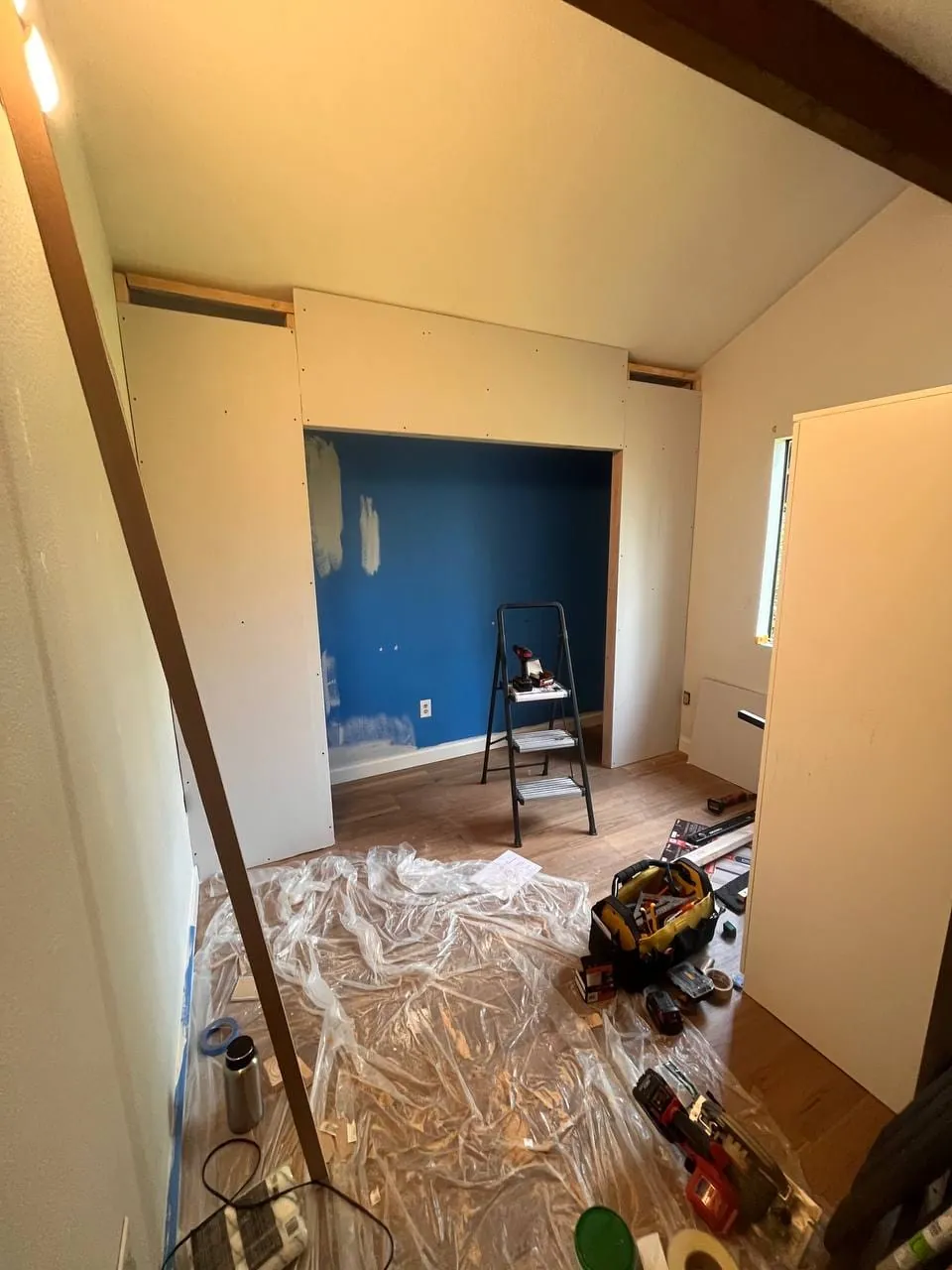 The closet framing covered in drywall, floor under plastic sheeting