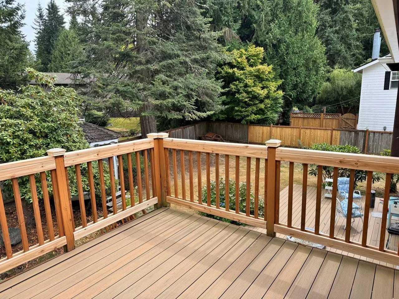 The finished railing around the deck, evergreens behind