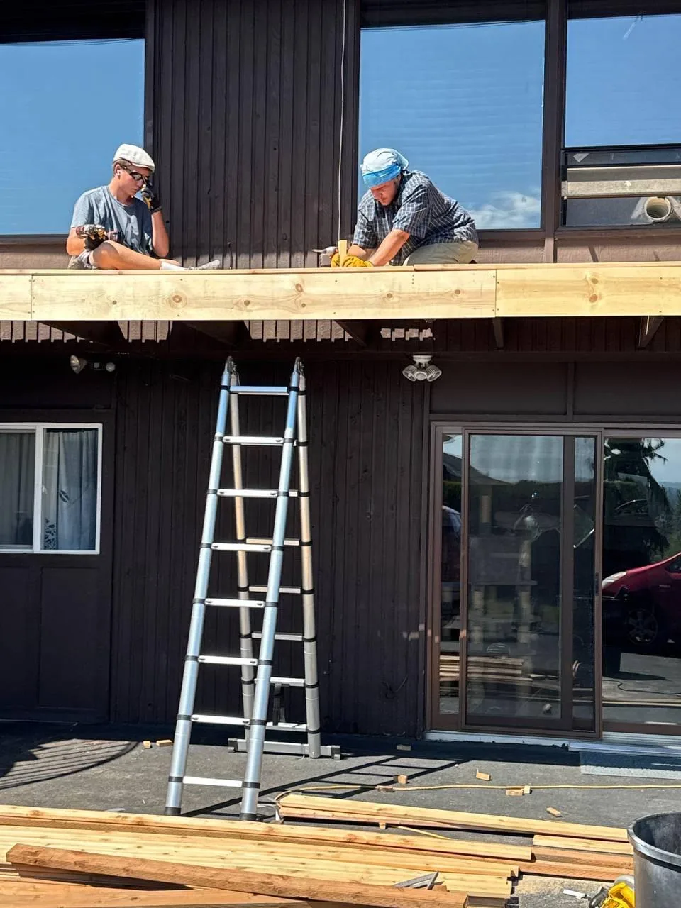 Two of the crew setting the new balcony frame, ladder against the wall
