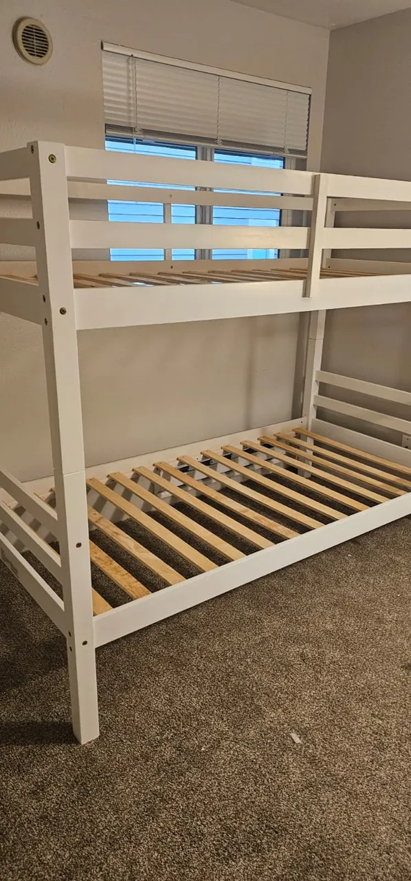 An assembled white bunk bed in a carpeted bedroom