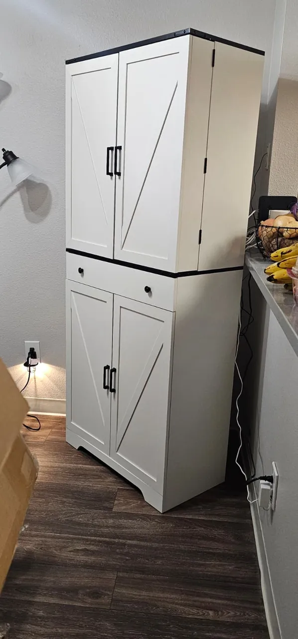 A tall white storage cabinet assembled and standing in a kitchen