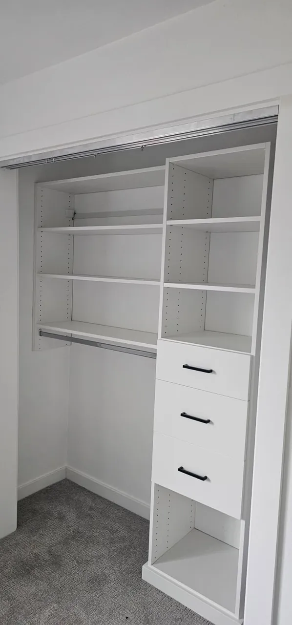 A closet shelving system with drawers installed in a reach-in closet