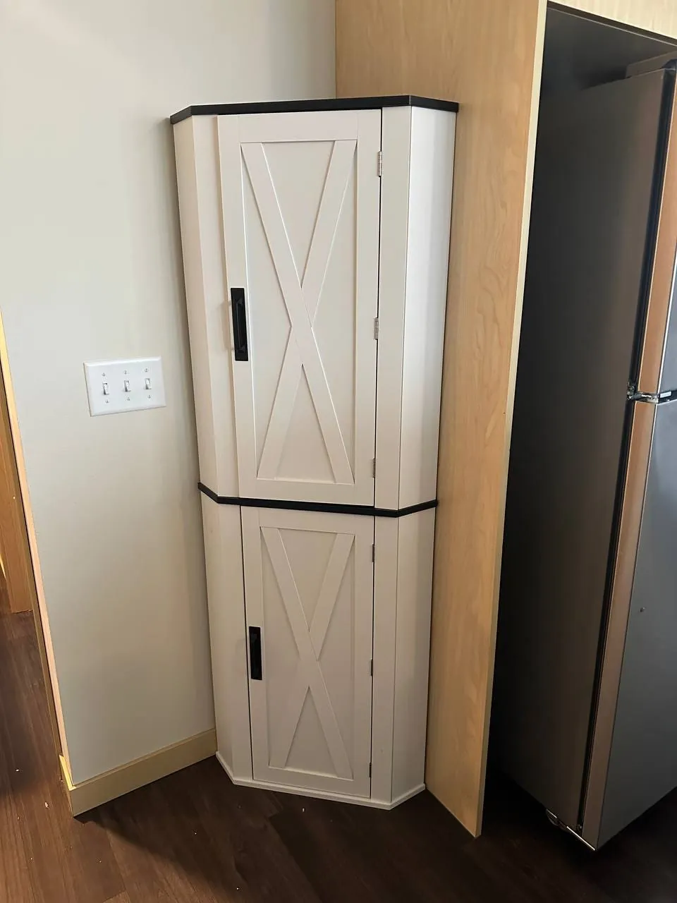 A white corner cabinet assembled beside a refrigerator