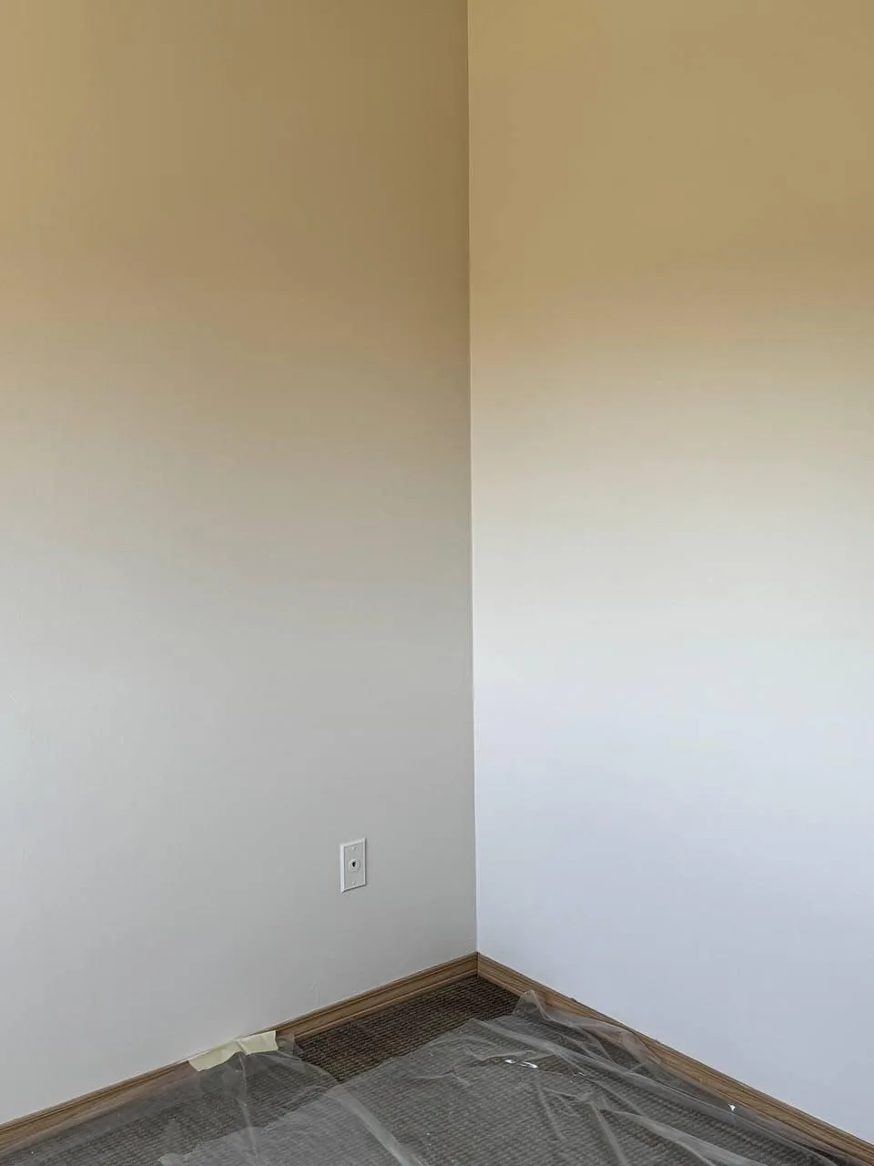 Corner of a room part-painted, the cut line between old and new colour visible