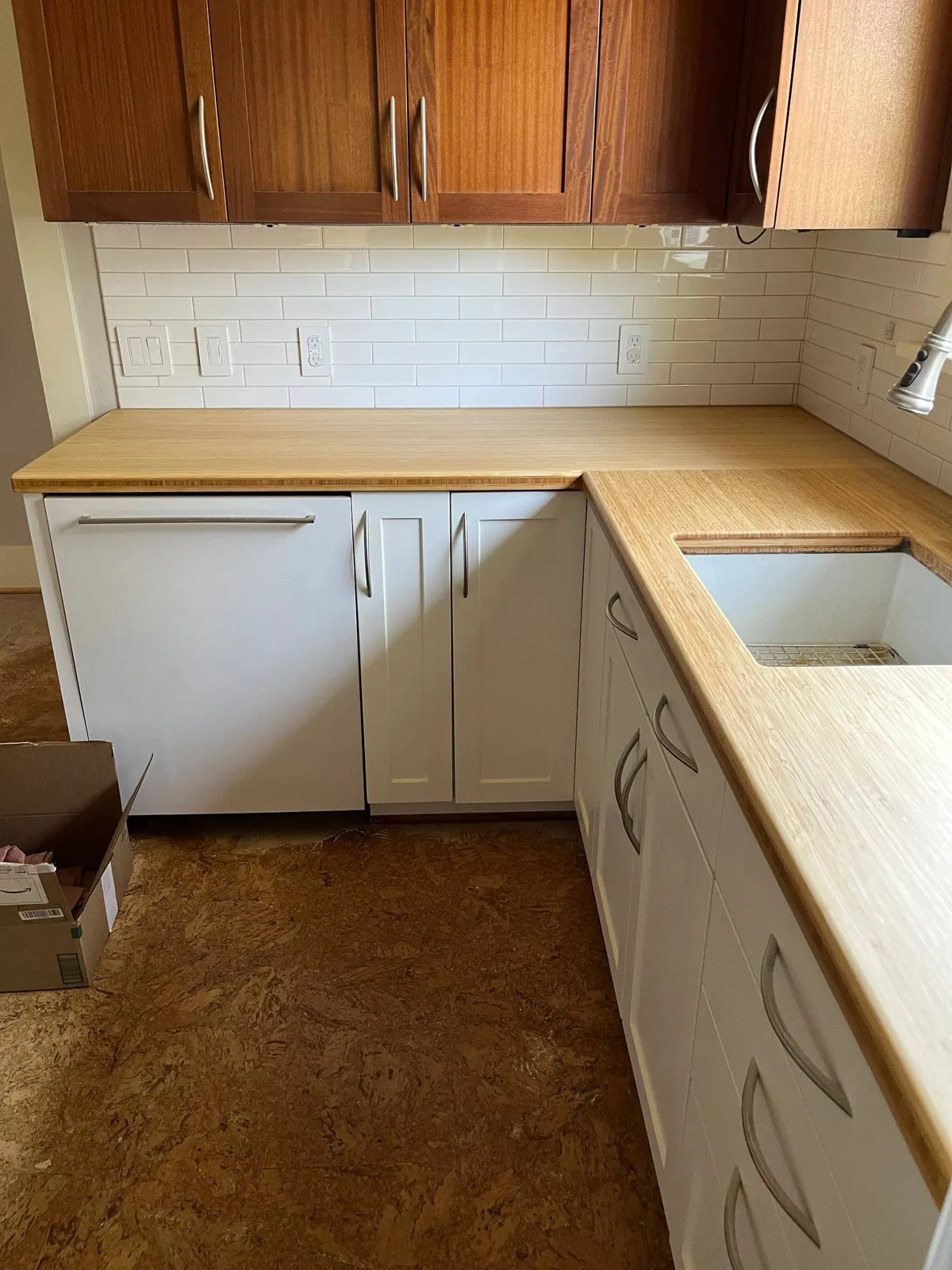 Fitted kitchen cabinets with a bamboo worktop, tiled splashback and undermount sink