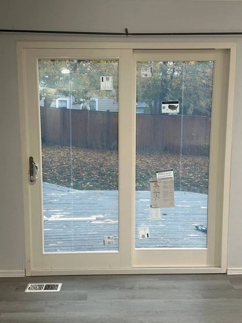 The new sliding patio door from the same spot inside, deck and fence beyond the glass