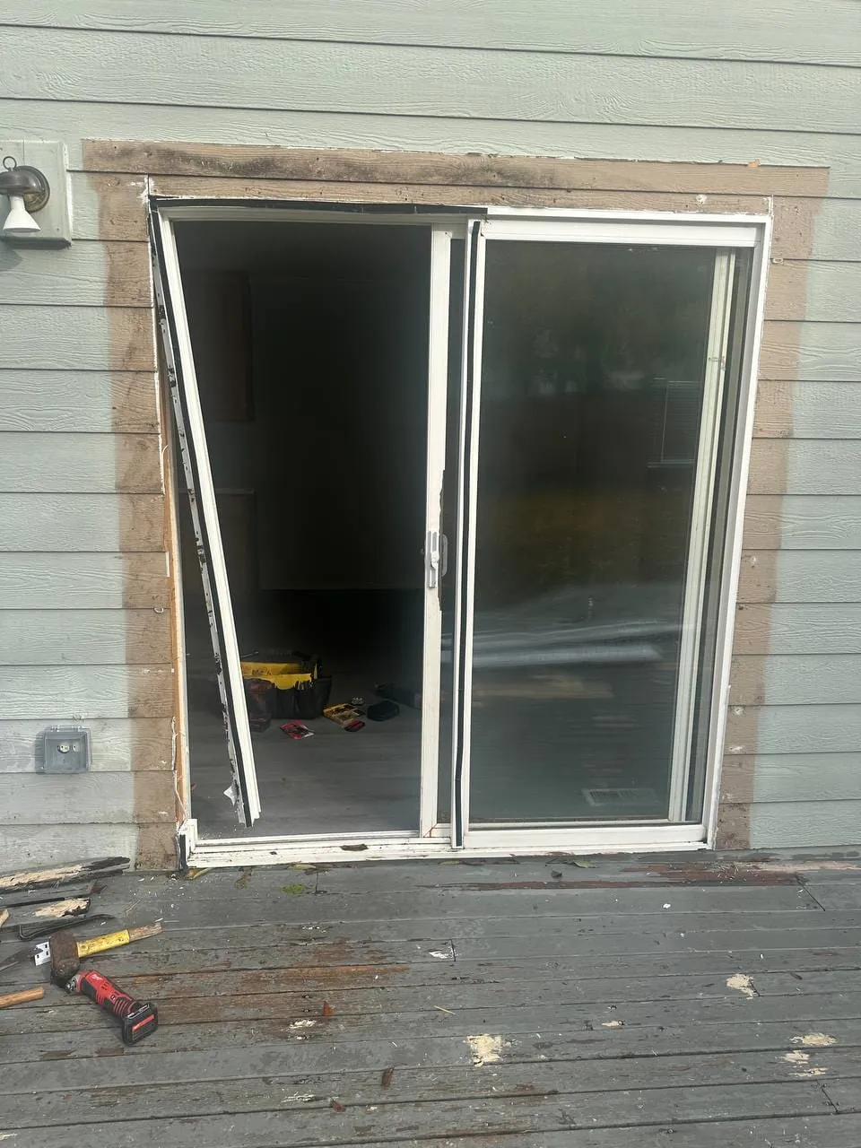 The old door being pulled from its frame, seen from the deck