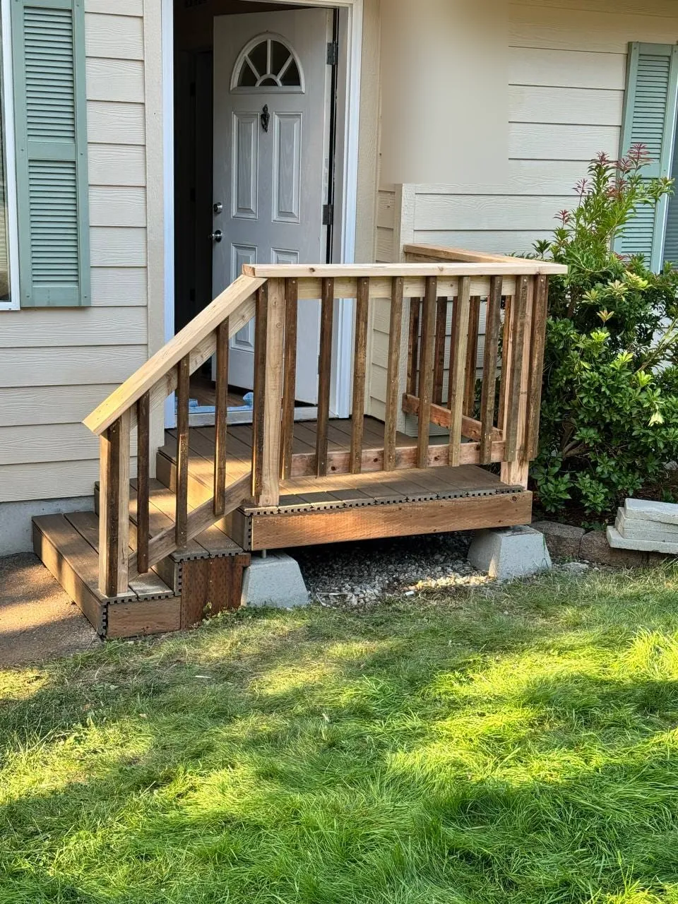 The old front porch on concrete blocks, with a wooden railing and metal-edged steps