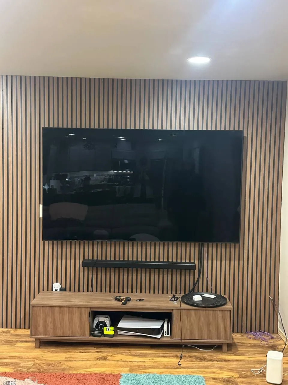The TV hung on the bracket with a soundbar below and a media console