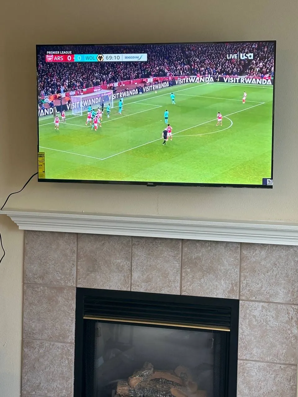 A TV mounted on the wall above a tiled gas fireplace